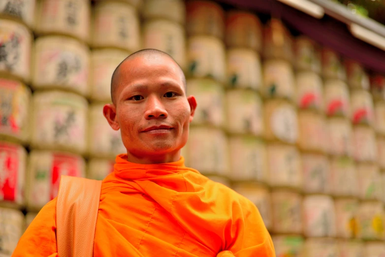 a young buddhist monk standing in front of lots of tea cans