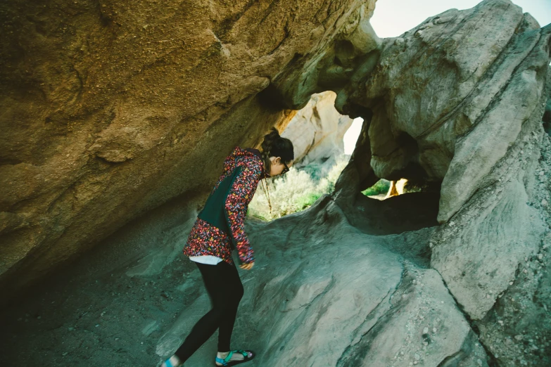 woman taking picture in front of a large rock formation