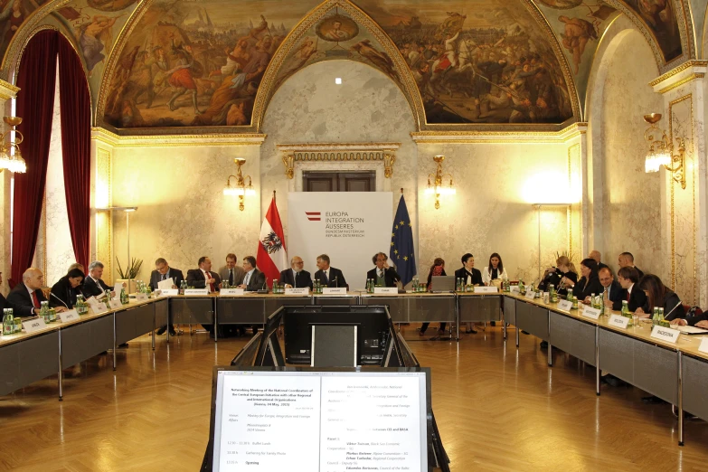 a meeting room filled with people sitting at long tables