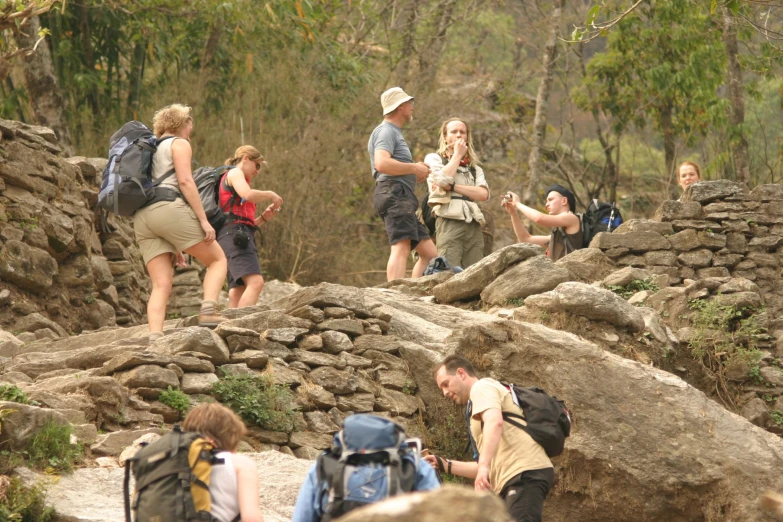 people with backpacks are standing around rocks and trees