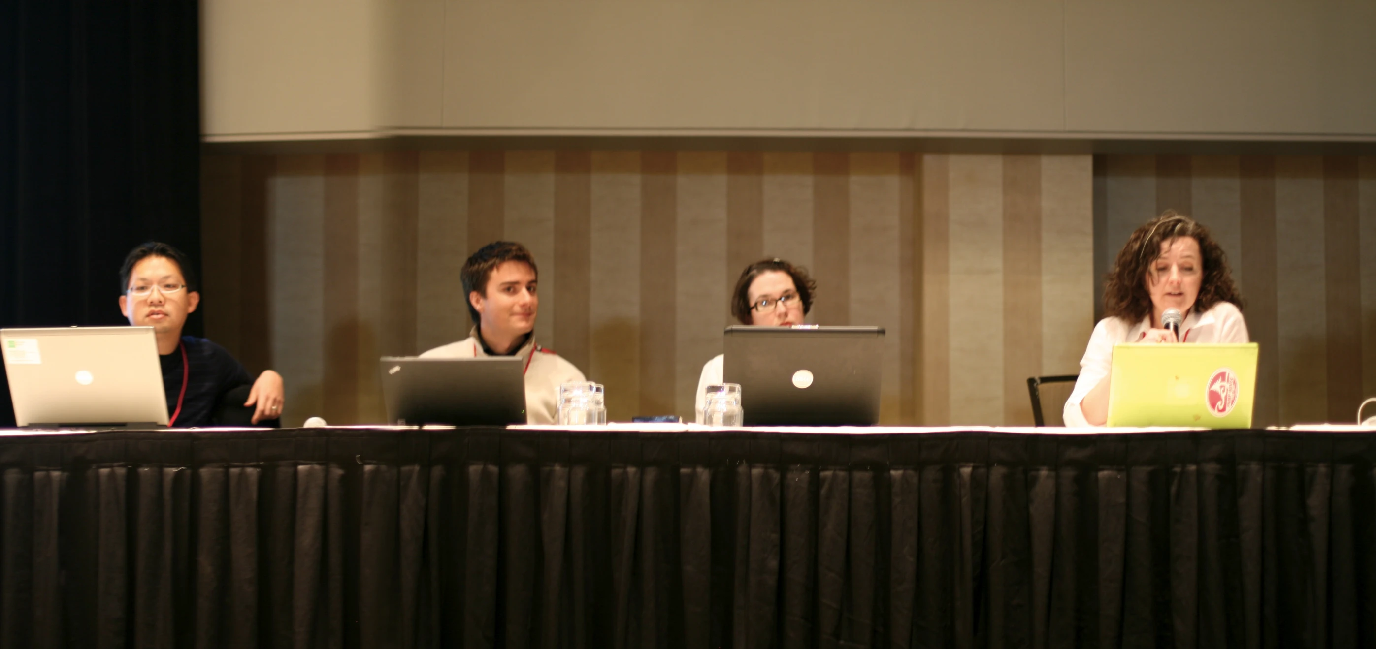 five people sitting at a table with laptops