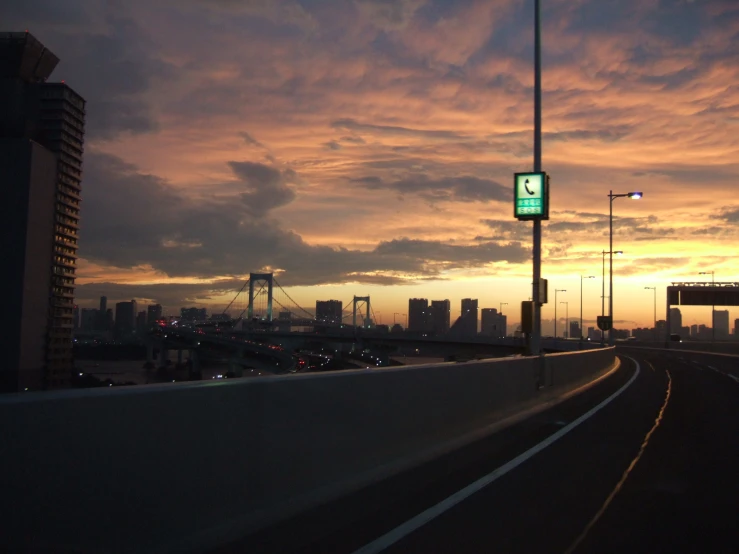 the sun sets over a highway with a city in the background