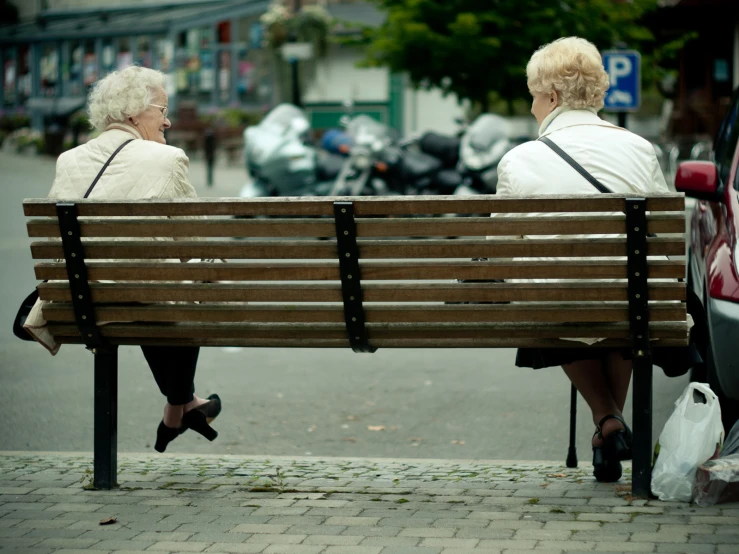 two women sitting on a bench looking at the street
