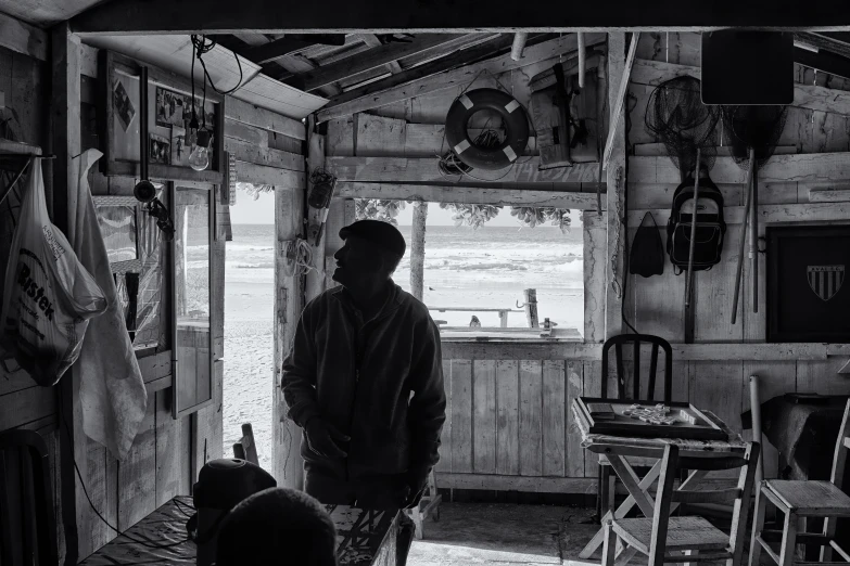 man stands in doorway of rustic cabin looking outside