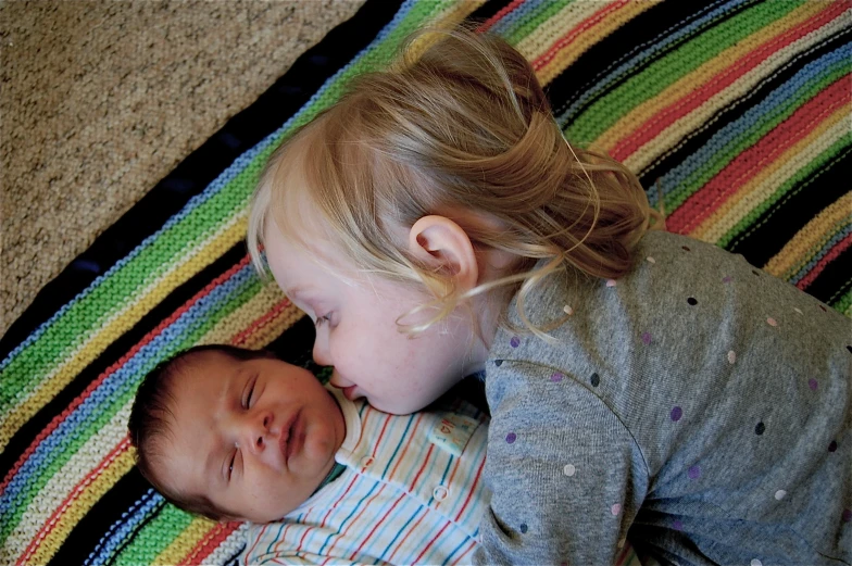 two baby children sleeping on a rug next to each other