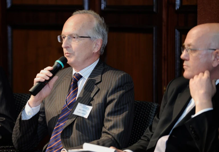 two men sitting side by side in front of a microphone