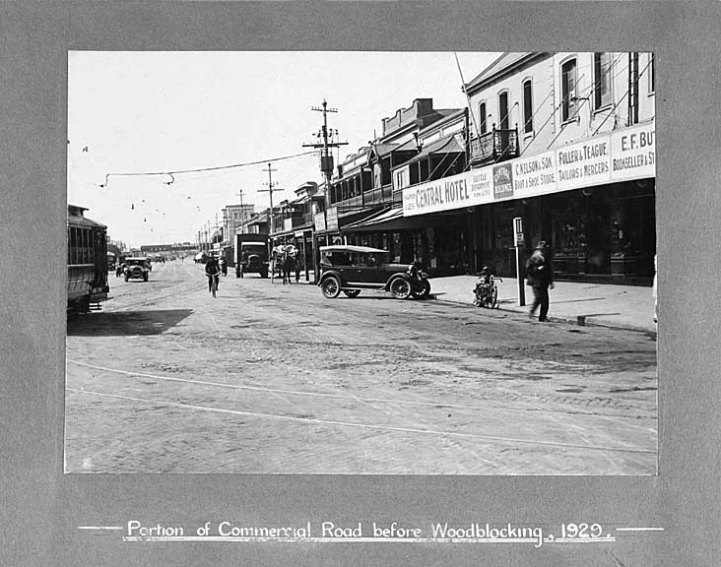 old black and white po of cars parked on the road in front of the buildings