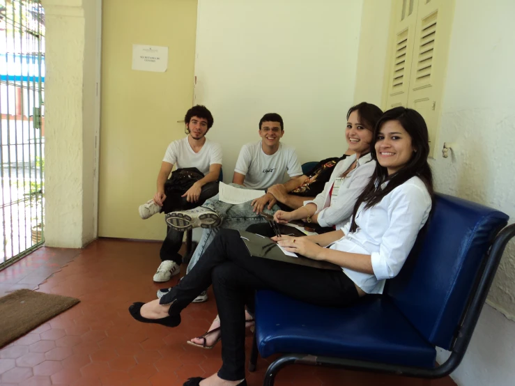 four people sit on a blue couch smiling