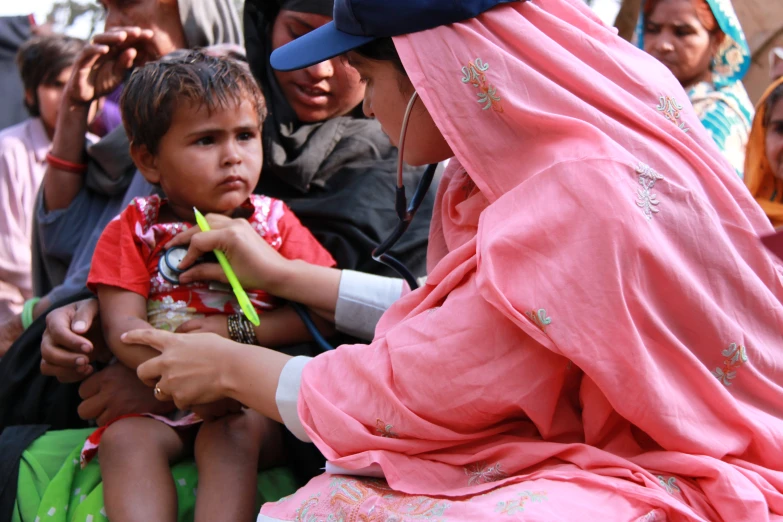 a woman in a headscarf gives a  soing to eat