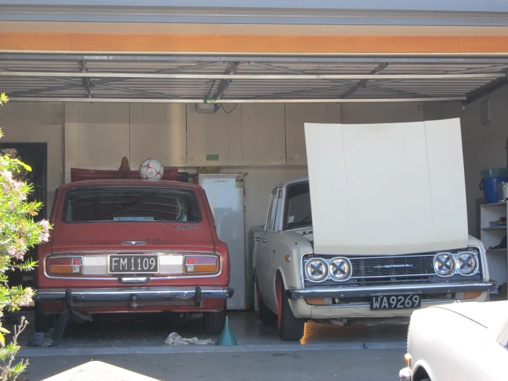 two old cars sitting in a garage with another car