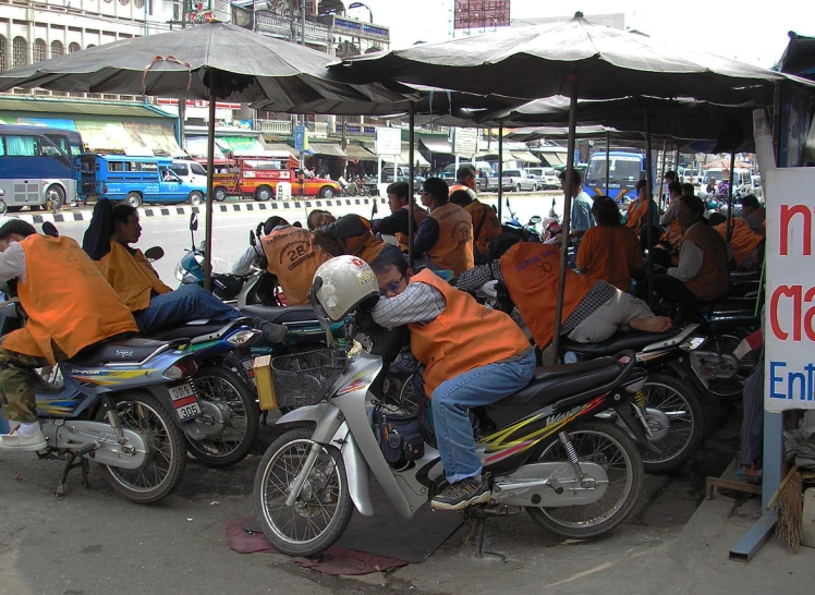 a group of people riding motorcycles with open umbrellas