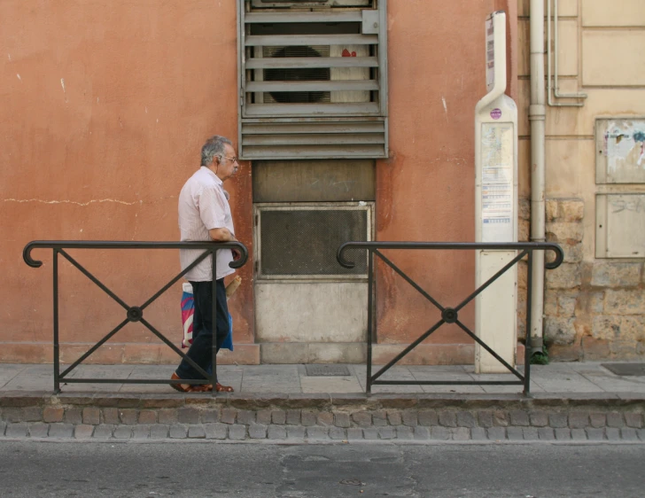 an older man on the side of the street leaning up against a rail