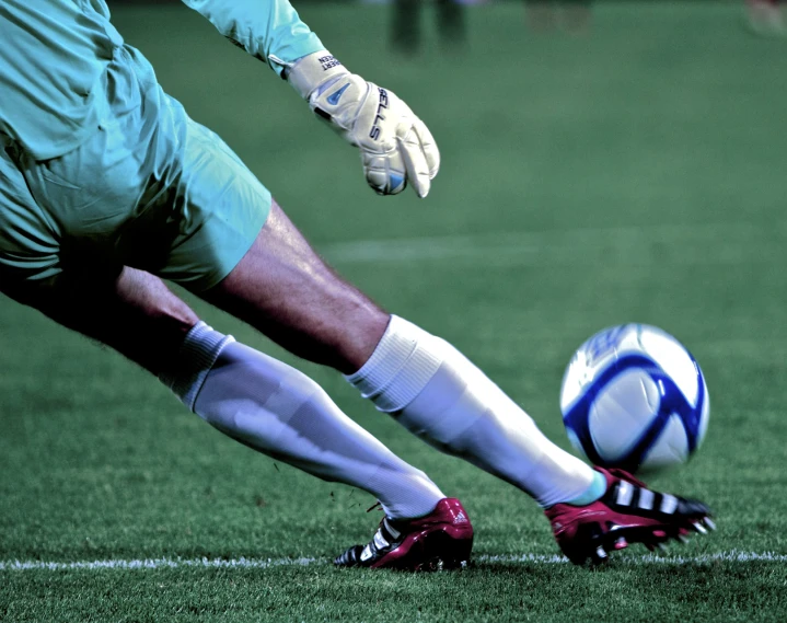 soccer player kicking ball in grassy field near goal