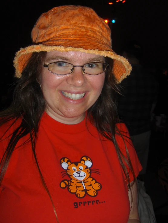 a girl wearing a red tshirt and a smiling hat