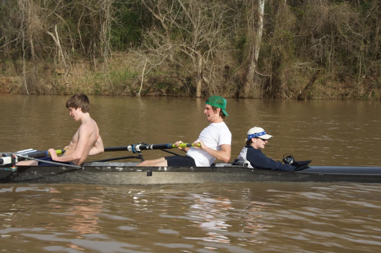 three young men riding in a boat down a river