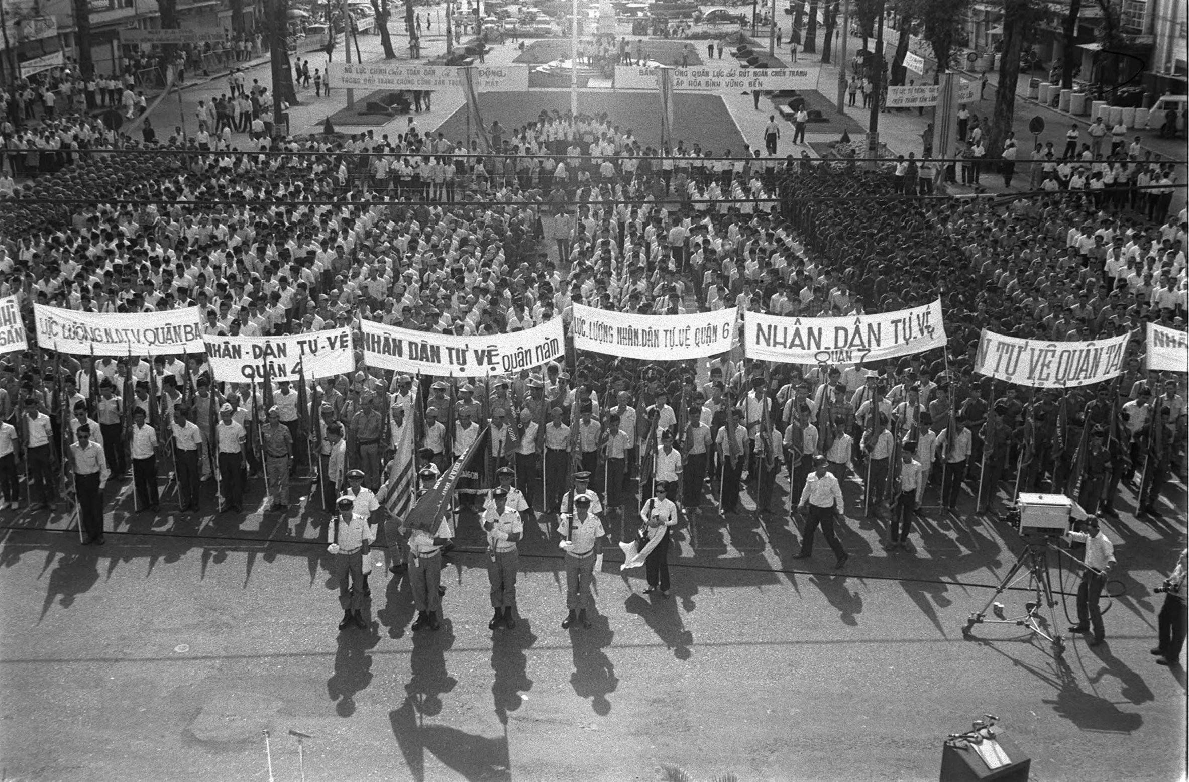 a crowd of people walking down a street holding up signs