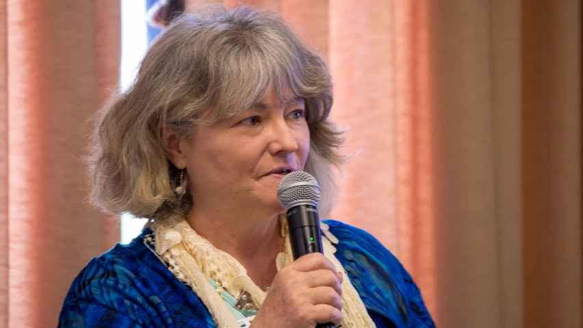 the woman is speaking into a microphone at a function