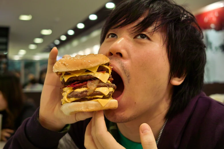 a man eating a large hamburger in a restaurant