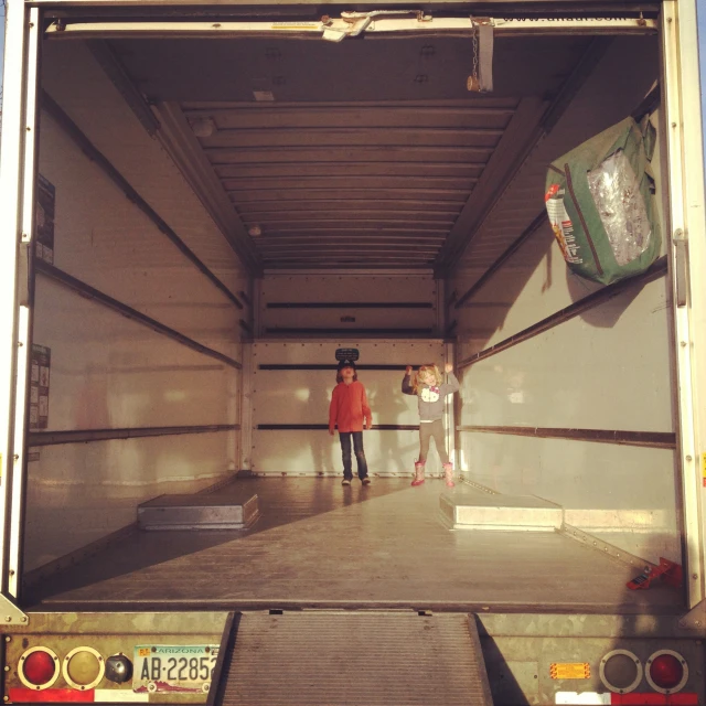 two people stand inside the back of a large container