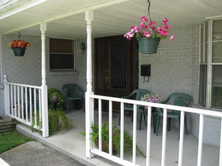 two flowers hanging over a porch area outside of a home