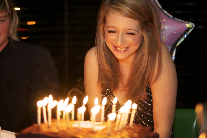 a  smiles as she blows out the candles on a birthday cake