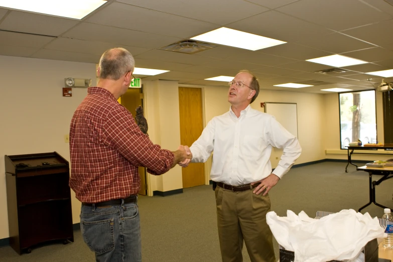 two men shake hands in an office building