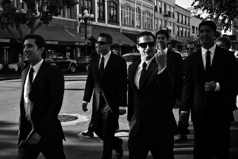 a man with his face covered by sun glasses walks in the street