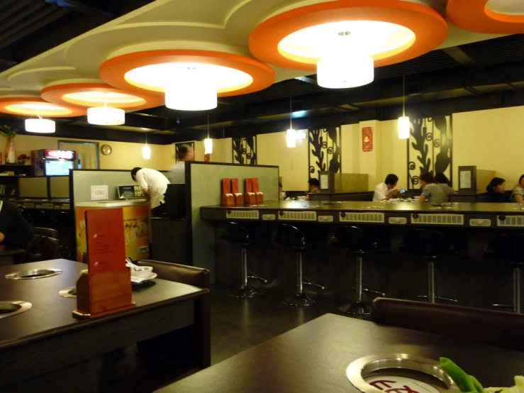 a restaurant with patrons sitting at tables under lights