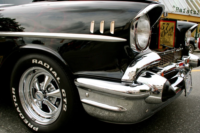 a black classic car with chrome trims parked on the side of a street