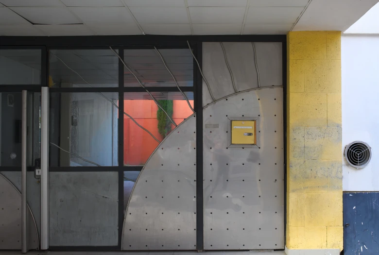 the yellow and blue wall has a door to a glass window with a spiral design