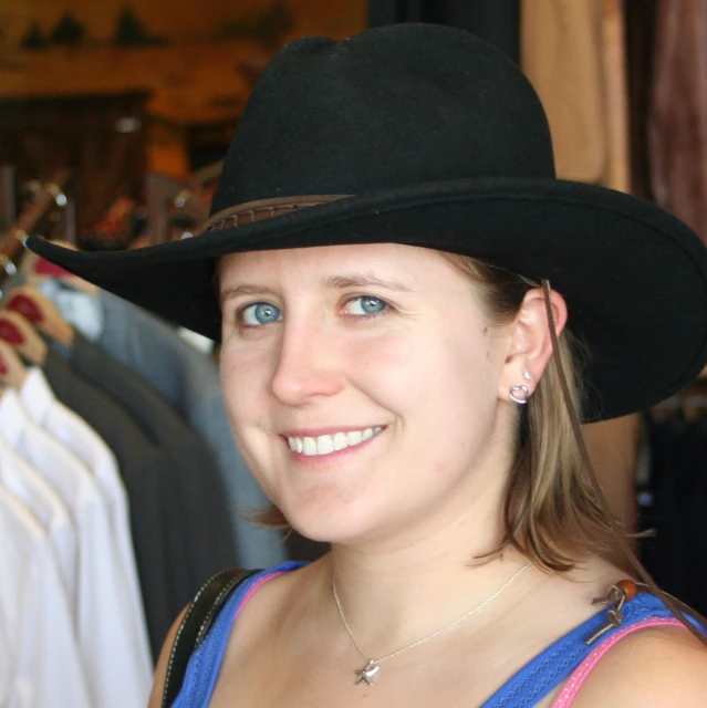 a woman wearing a large black hat and holding her hand on her hips