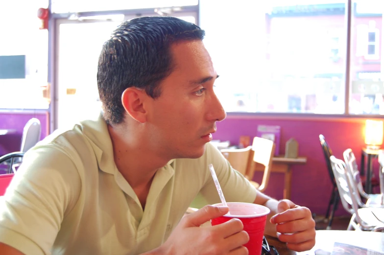 a man looking away from the camera holding a drink in front of him