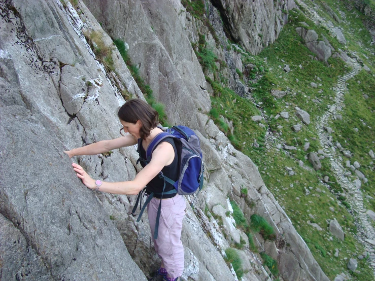 young woman climbing on top of rocky cliff