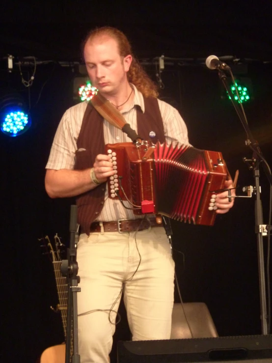 man with long hair playing an accordion at an event
