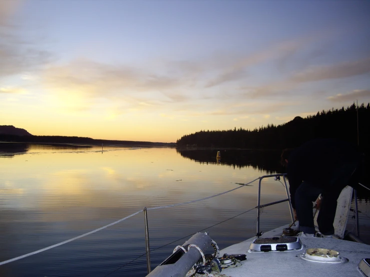 a man is preparing his boat for sunset on the water