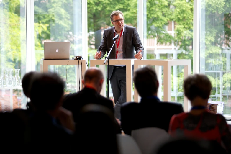 a man in suit and tie speaking from a podium at an event