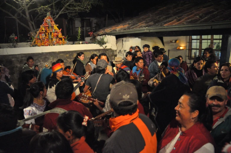 a group of people outside at night with some musicians