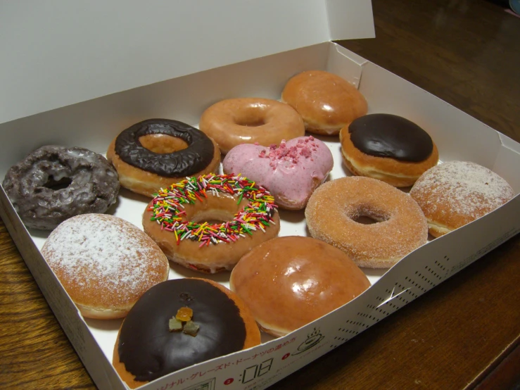 a box of various donuts on a wooden table