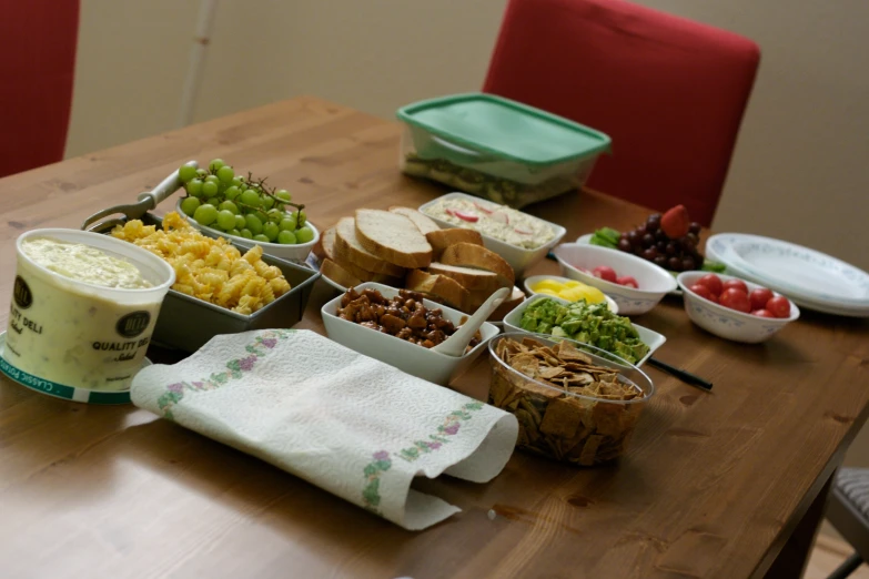 a table topped with plastic containers of fruit and bread