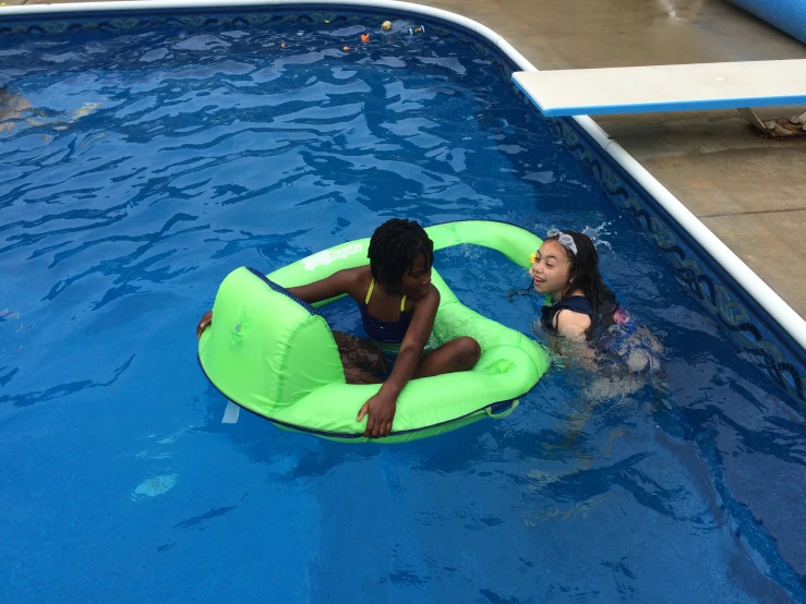 two girls in an inner tube swim through the water