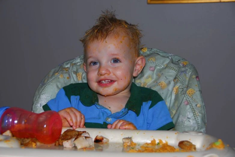 a young child sitting in a high chair, eating