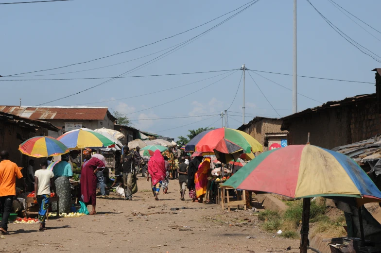 people standing under colorful umbrellas in a small village