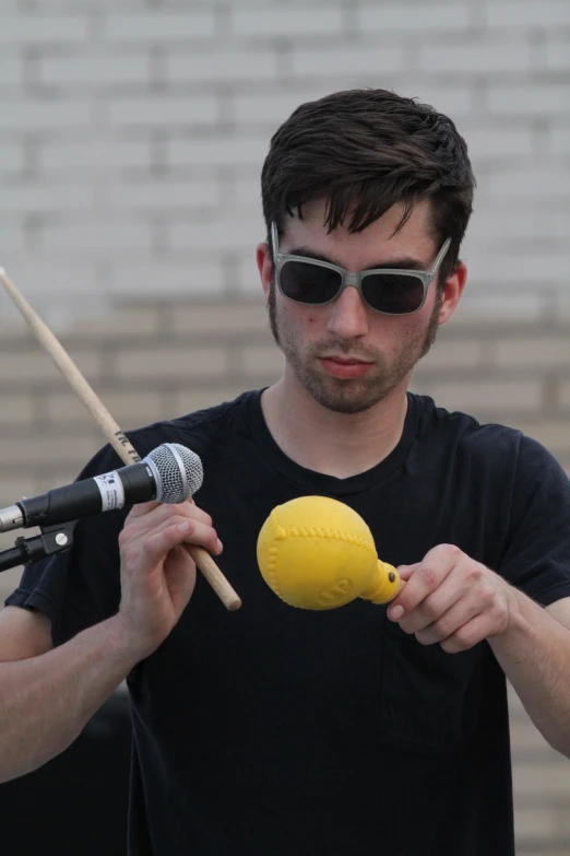 man in sunglasses and black shirt playing with yellow instrument