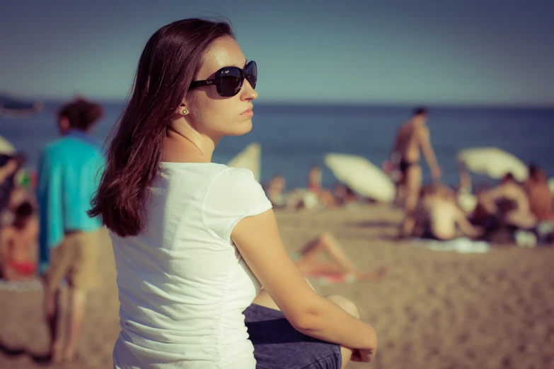 the woman is staring at the beach, while others are in their swimsuits