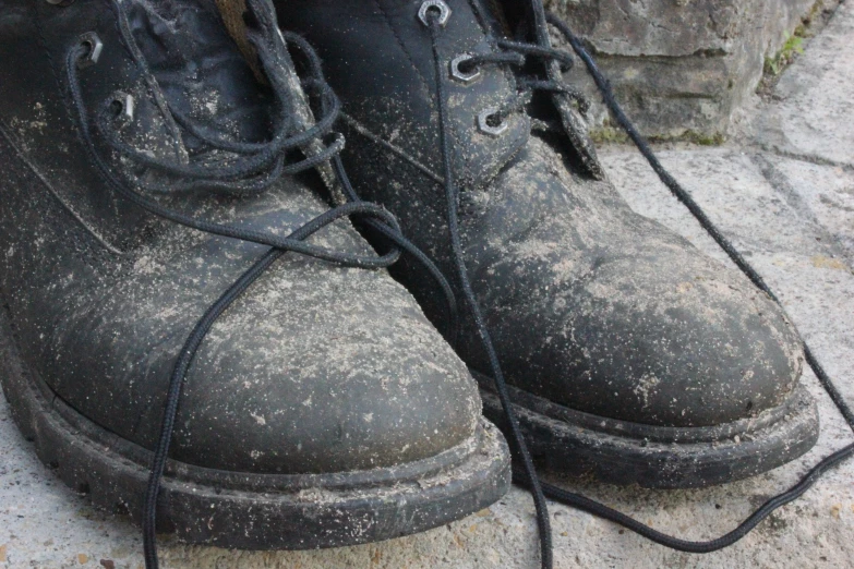 worn black boot on concrete near stone wall