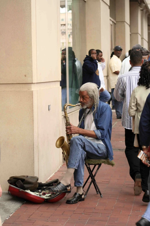 the man is sitting on a chair playing his saxophone