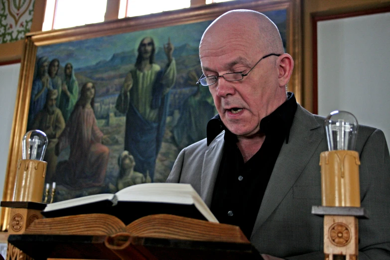 a priest holding a bible in front of paintings