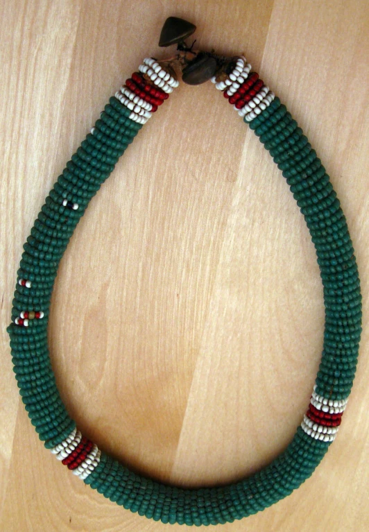 a green beaded necklace sitting on top of a wooden table