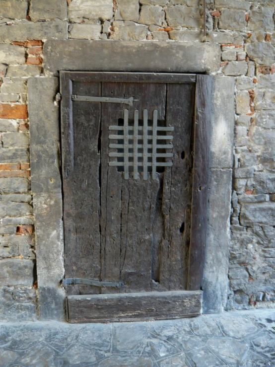 an old and weathered wooden door with a metal grate