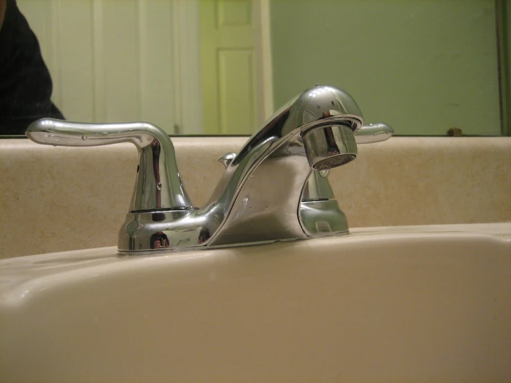 a small silver faucet sits on a bathroom sink